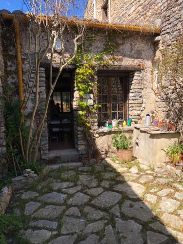 een stenen huis met een deur en een patio bij MAISON PIERRE 128M JARDIN TERRASSE 5 MM SOMMIERES in Aspères