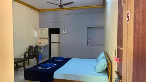 a small bedroom with a blue bed and a sink at Coco Hut , Devbaug in Malvan