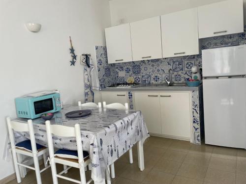 uma cozinha com uma mesa com cadeiras e um micro-ondas em Case del Mar em Santa Teresa Gallura