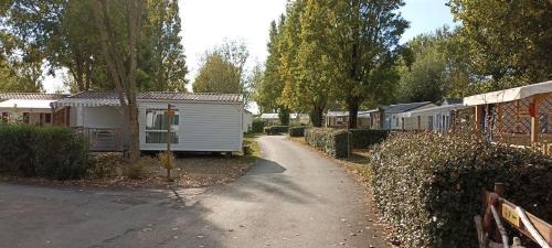 a white trailer parked next to a road with houses at Mobilhome L'Oasis Camping le Clos Cottet in Angles