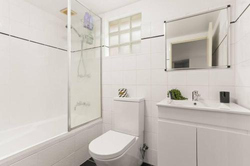 Cosy Inner City Abode - 1 Bed Woolloomooloo في سيدني: حمام ابيض مع مرحاض ومغسلة