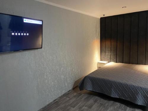 1 dormitorio con 1 cama y TV en la pared en Апартаменты, en Semey