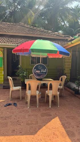 a table with chairs and a colorful umbrella at Coco Hut , Devbaug in Malvan