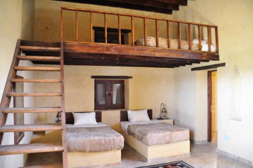 a bedroom with two bunk beds and a ladder at El Beyt Farmhotel in Az Zabū