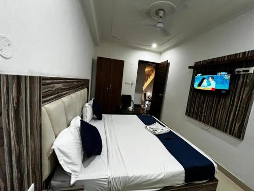 a bedroom with a bed with a tv on the wall at wide Hotel in New Delhi