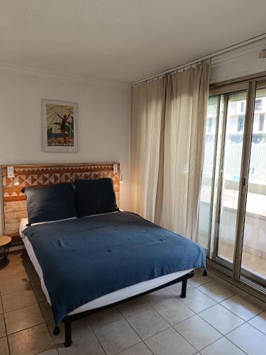 une chambre avec un lit avec des draps bleus et une fenêtre dans l'établissement Promenade résidence hoteliére, à Nice