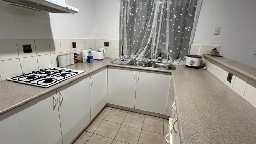 a white kitchen with a stove and a sink at Bickley Street in Perth