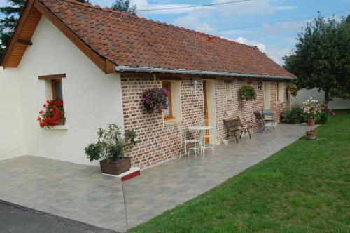a brick house with a patio in front of it at Au Clos du Logis in Maintenay