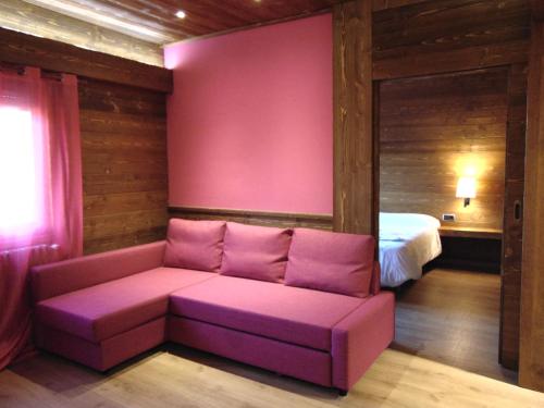 a pink couch in a room with a bed at Hostal Piteus in Sant Llorenc de Morunys