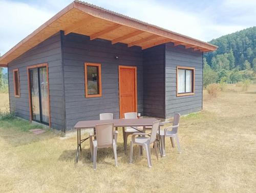 a table and chairs in front of a tiny house at Cabaña Kallfü Mahuida in Panguipulli