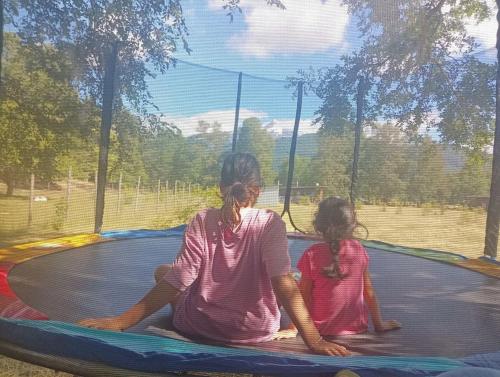 a woman and a child sitting on a trampoline at Cabaña Kallfü Mahuida in Panguipulli