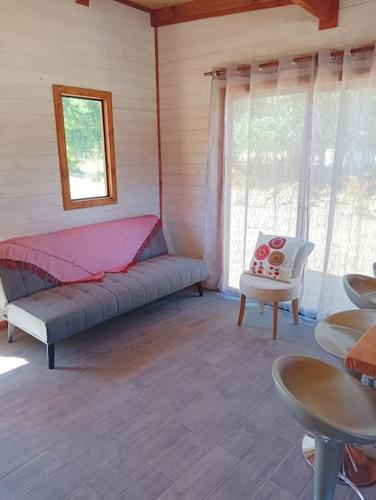 a room with a bed and a chair and windows at Cabaña Kallfü Mahuida in Panguipulli