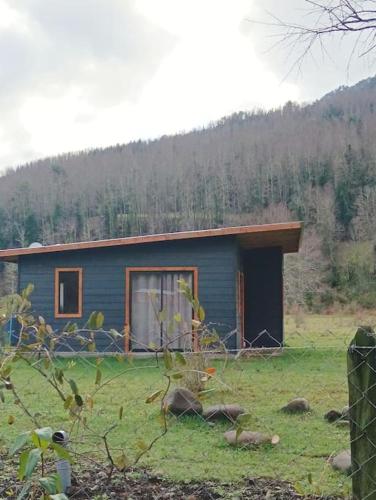 a small blue house in the middle of a field at Cabaña Kallfü Mahuida in Panguipulli