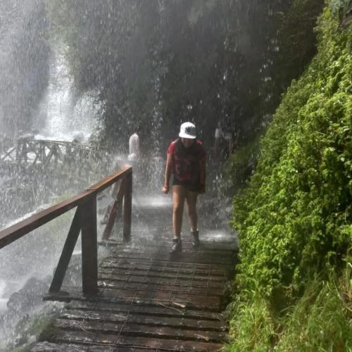 a woman walking down a bridge in the rain at Cabaña Kallfü Mahuida in Panguipulli