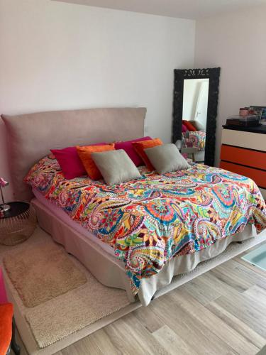 a bed with a colorful blanket and pillows in a bedroom at Maison proche de la Loire in Saint-Georges-de-Baroille