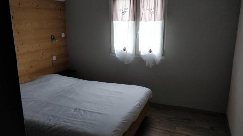a small bedroom with a bed and two windows at Les terrasses des bouleaux Gîtes et Chalets SPA in Ranspach