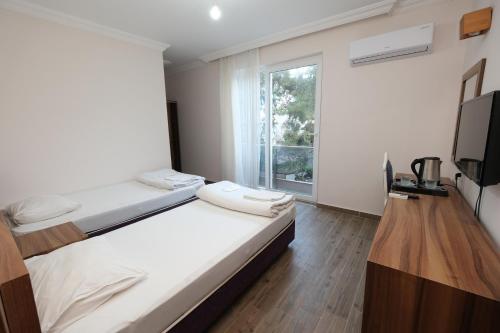 a bedroom with two beds and a tv and a window at Venüs Hotel in Antalya