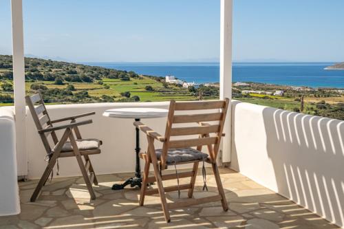 a balcony with two chairs and a table and the ocean at VILLA ALYKI SEA VIEW PAROS in Kampos Paros