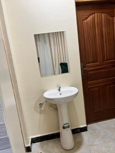 y baño con lavabo blanco y espejo. en Art’s Suites en Kisumu