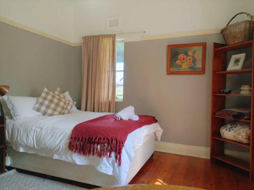 a bedroom with a bed with a red blanket at Riverview Country Inn in Van Reenen