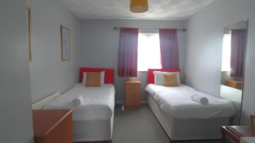 a small bedroom with two beds and a window at Eddiwick House - Huku Kwetu Dunstable -Spacious 3 Bedroom House- Sleeps 6 - Suitable & Affordable Group Accommodation - Business Travellers in Houghton Regis