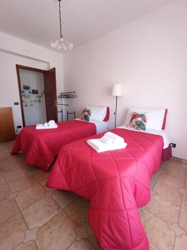 2 letti con coperte rosse in una camera di La Casa Sicula a Capri Leone
