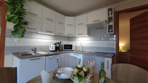 ガールドニにあるLimonádé Apartmanの白いキャビネットと花のテーブル付きのキッチンが備わります。