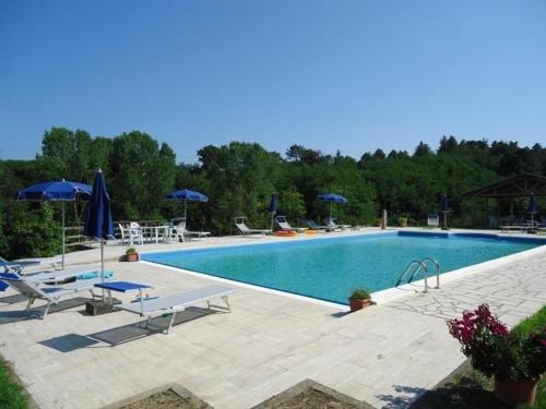 una gran piscina con sillas y sombrillas en Ferienwohnung für 8 Personen ca 170 qm in Fauglia, Toskana Etruskische Küste, en Fauglia