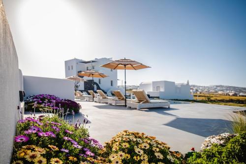 a patio with chairs and umbrellas and flowers at Bonsai Luxury Suites in Karterados