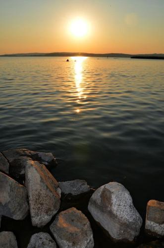 a sunset over a large body of water with rocks at Limonádé Apartman AC Agárd Élményfürdő mellett in Gárdony