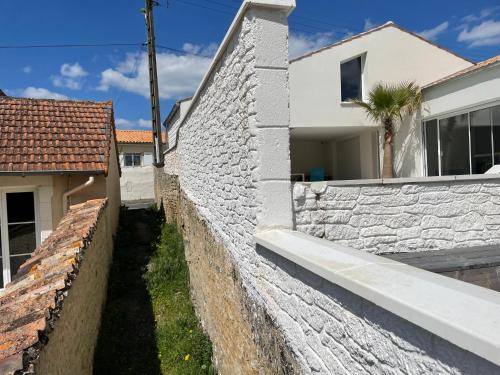 un mur en pierre à côté d'une maison blanche dans l'établissement Villa Ioda, à Chasseneuil-du-Poitou