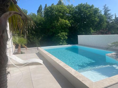 - une piscine avec une chaise à côté dans l'établissement Villa Ioda, à Chasseneuil-du-Poitou