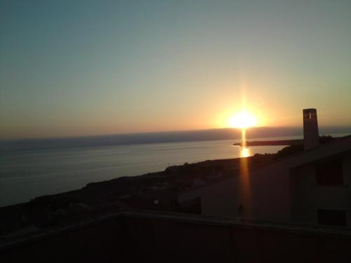 a sunset over the water with a lighthouse in the distance at Amazing BAY VIEW-BEACH BOUTIQUE Apartment VELAMEIGA in Funtana Meiga