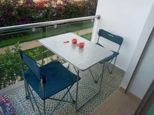 een tafel en 2 stoelen met rode kopjes op een balkon bij Cozy appartement à Mansouria res fermé 4 piscines in Mansouria