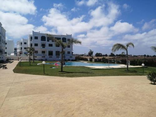een zwembad in een park met een gebouw en palmbomen bij Cozy appartement à Mansouria res fermé 4 piscines in Mansouria