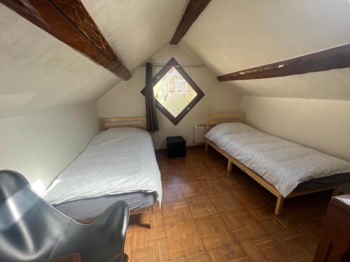 ein Dachzimmer mit zwei Betten und einem Stuhl in der Unterkunft Duplex Cosy Centre Ville in Saint-Leu-la-Forêt