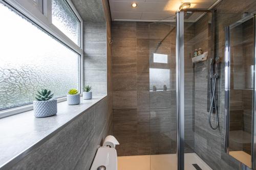 een badkamer met een douche en een glazen deur bij AvenueHouse-Airport-FREEParking&WIFI in Baguley