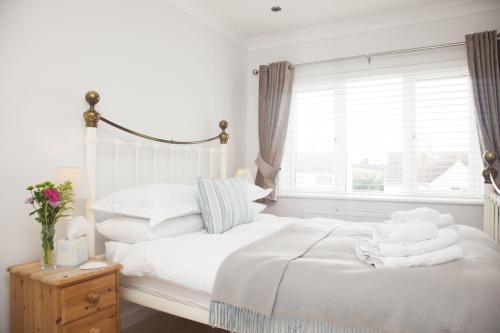 a bedroom with two beds with white sheets and a window at Trevose House in Padstow