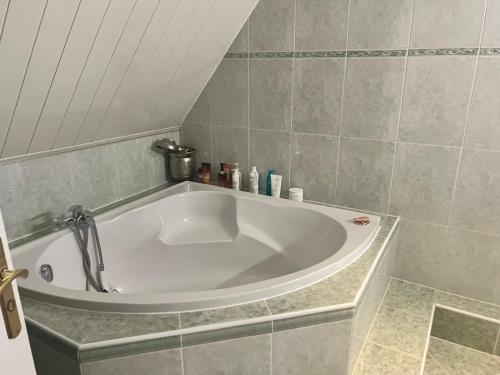 a large white tub in a tiled bathroom at Maisons d'hôte à la campagne Parisienne in Longjumeau