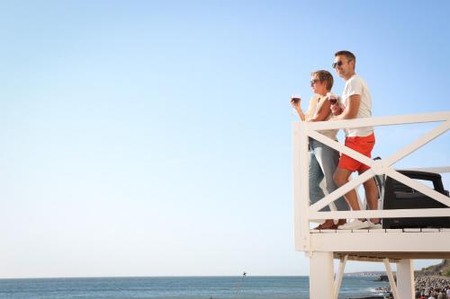 a man and a woman standing on a dock on the beach at La Goélette, Chambres d'Hôtes in Wimereux