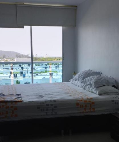 Bett in einem Zimmer mit einem großen Fenster in der Unterkunft Apartamento mirador de la sierra 2 in Valledupar