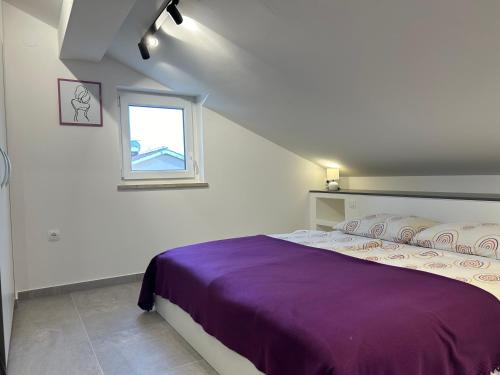 a bedroom with a purple bed and a window at Apartments Žic Malinska in Malinska
