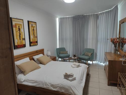 a hotel room with a bed and two chairs at Ashkelon a front of the sea in Ashqelon