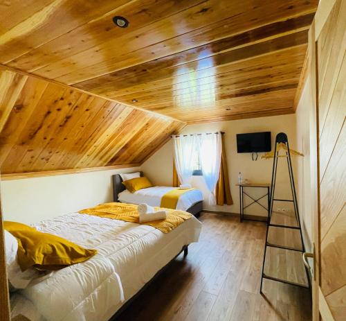 two beds in a room with wooden ceilings at Au sommet des Salazes in Salazie