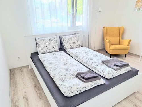 a bed with two pillows and a chair in a room at Garsónka v Bratislave in Bratislava