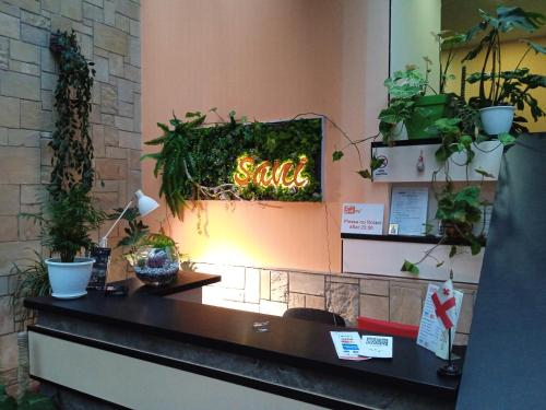 a desk with a sign on a wall with plants at Sani Hotel in Tbilisi City