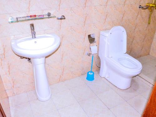 a bathroom with a white toilet and a sink at KEZA Home in Kigali