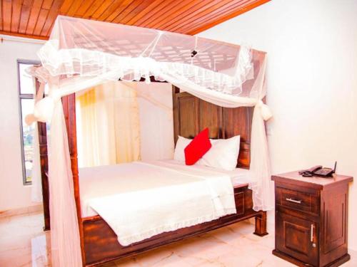 キガリにあるKEZA Homeのベッドルーム(天蓋付きベッド1台、ナイトスタンド付)