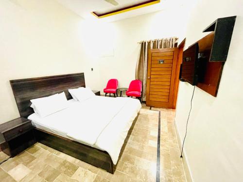 卡拉奇的住宿－Hotel Highway Link，一间卧室配有一张床和两张红色椅子