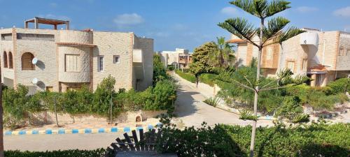 a building with a palm tree next to a street at شاليه في قرية هيلو بيتش في الكيلو ٥٠ in Borg El Arab